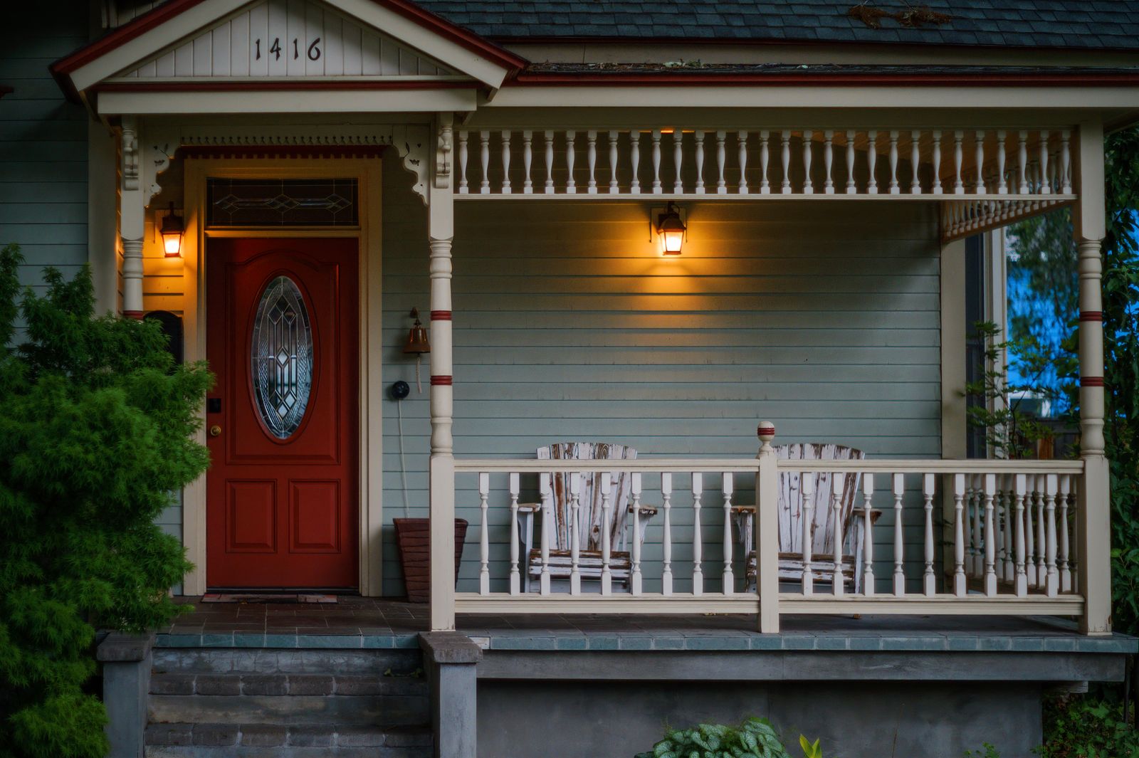 Le porche éclairé d'une maison le soir, porte d'entrée rouge