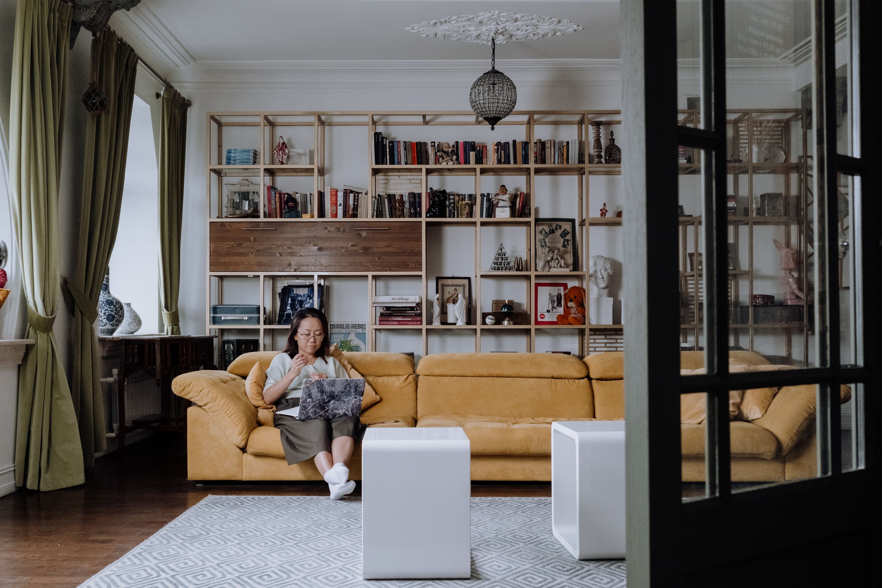 Une femme lit sur un canapé dans un grand salon aux murs de livres